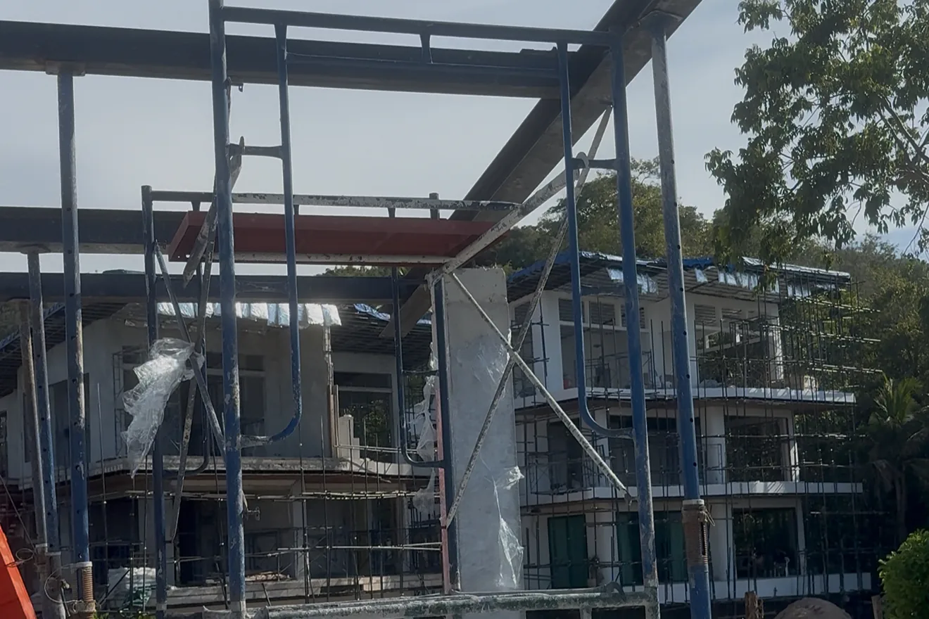 Steel roof frame going up at Gaia Residence in September 2026, with the rendered and glazed lower buildings behind