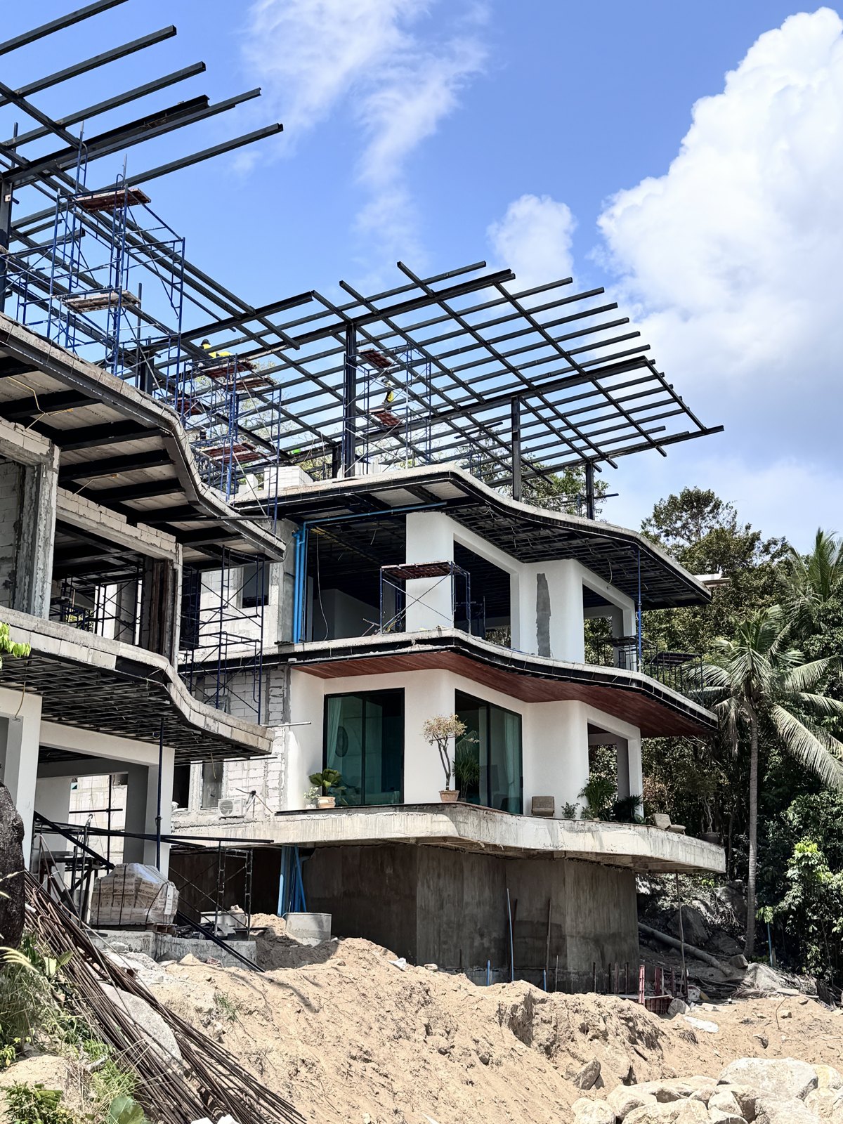 Finished curved facades at Gaia Residence with the steel roof structure rising above, Chaloklum, Koh Phangan